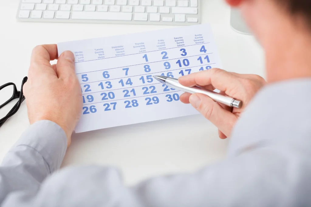 Personne pointant avec stylo les dates d'un agenda papier