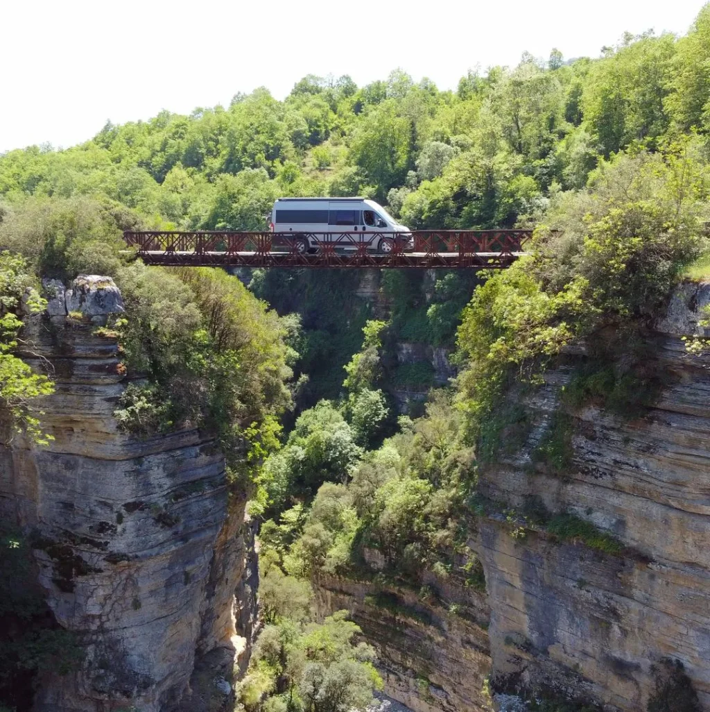 Passage sur un pont suspendu entre deux falaises avec un fourgon aménagé