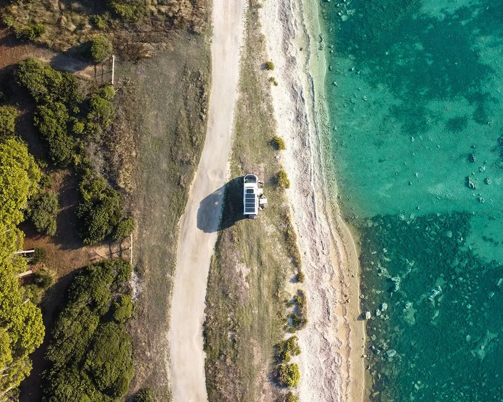 Fourgon aménagé en van isolé en bord de mer et vu du ciel